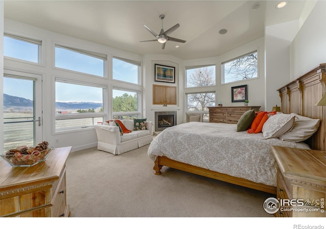 bedroom featuring carpet floors, a fireplace, a towering ceiling, a mountain view, and access to outside