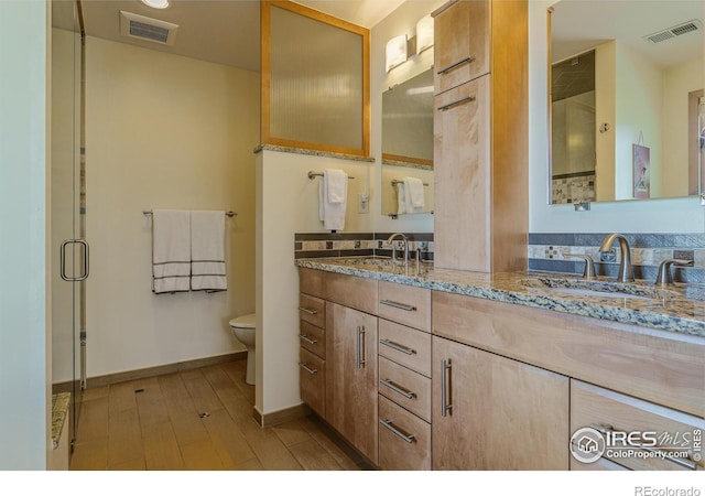 bathroom with toilet, wood finished floors, visible vents, and a sink