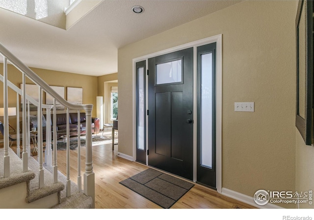 foyer entrance featuring stairs, wood finished floors, and baseboards