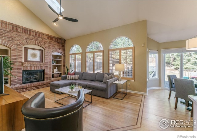 living area with a healthy amount of sunlight, a fireplace, high vaulted ceiling, and wood finished floors