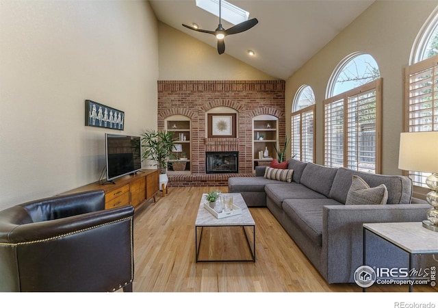 living room with a fireplace, high vaulted ceiling, wood finished floors, and a ceiling fan