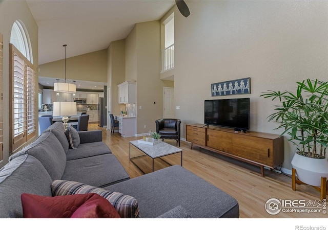 living room featuring light wood-type flooring, baseboards, and vaulted ceiling