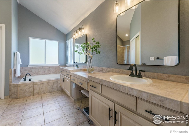 full bathroom with tile patterned floors, a garden tub, lofted ceiling, and a sink