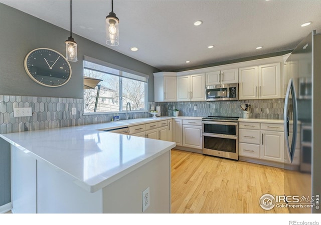 kitchen featuring white cabinetry, a peninsula, stainless steel appliances, and a sink