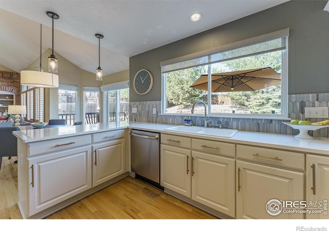 kitchen featuring a peninsula, a sink, light countertops, dishwasher, and light wood-type flooring