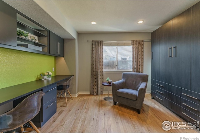 office space featuring built in desk, recessed lighting, baseboards, and light wood-style floors