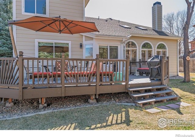 back of property with a shingled roof, a wooden deck, and a chimney