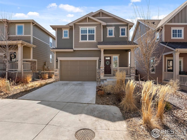 craftsman-style house featuring stone siding, covered porch, concrete driveway, and a garage