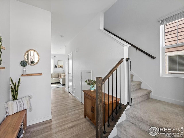 stairway with wood finished floors and baseboards