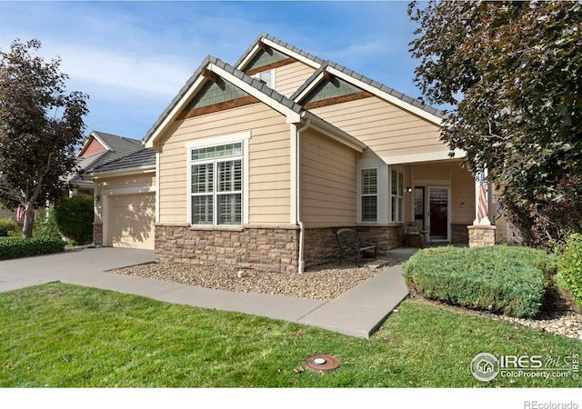 craftsman inspired home featuring a tiled roof, concrete driveway, a front yard, stone siding, and an attached garage