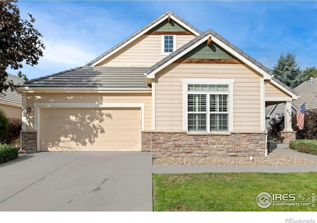 view of front facade featuring a tiled roof, an attached garage, stone siding, and driveway