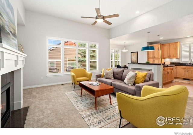 living area featuring recessed lighting, a fireplace with flush hearth, light carpet, and a healthy amount of sunlight