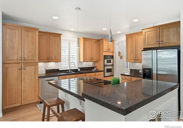 kitchen featuring light wood-style flooring, recessed lighting, a sink, appliances with stainless steel finishes, and a kitchen breakfast bar