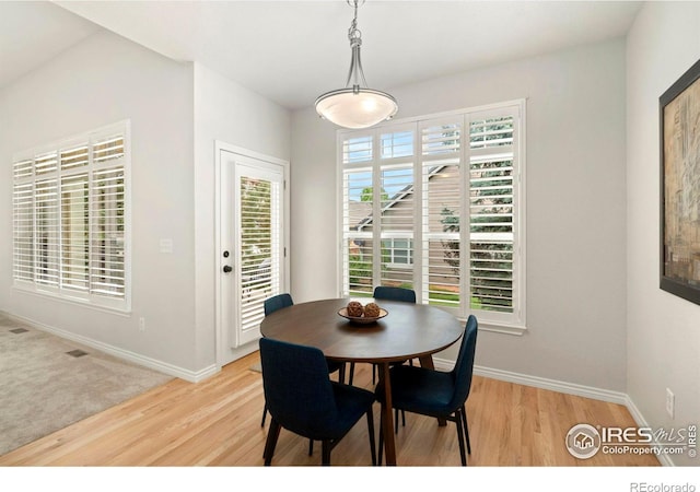 dining space with baseboards and light wood-type flooring