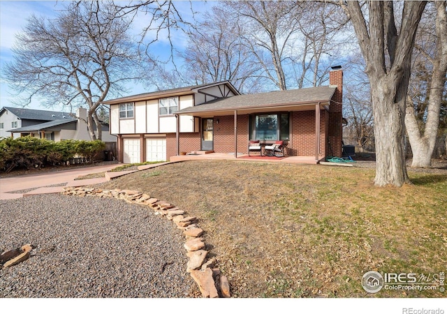 tri-level home featuring driveway, a front lawn, an attached garage, brick siding, and a chimney