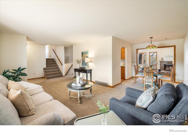 living area featuring visible vents, stairway, a lit fireplace, baseboards, and light colored carpet