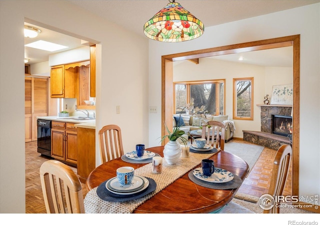 dining space with a stone fireplace and vaulted ceiling