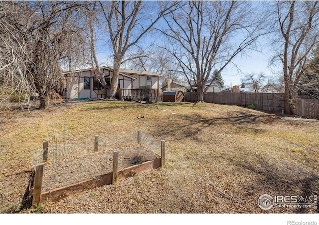 view of yard with an outbuilding, a vegetable garden, a storage unit, and fence