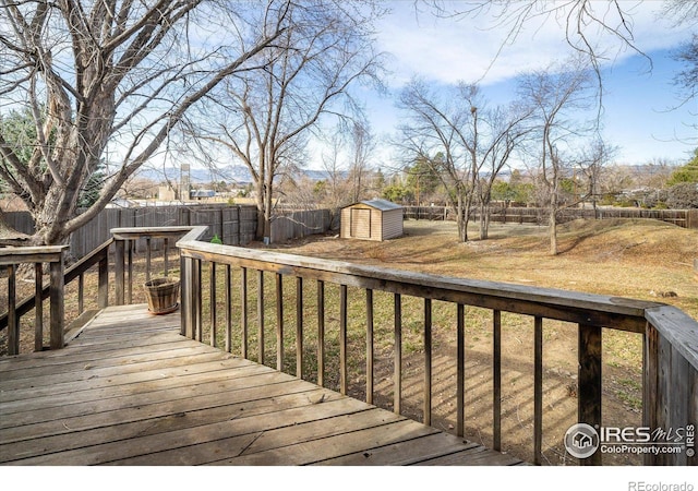 deck with an outbuilding, a fenced backyard, a lawn, and a shed