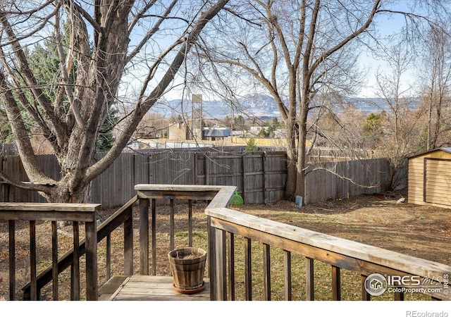 wooden deck with a storage shed, an outdoor structure, and a fenced backyard