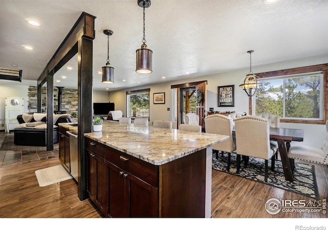 kitchen featuring light stone countertops, open floor plan, dark wood-style flooring, and hanging light fixtures