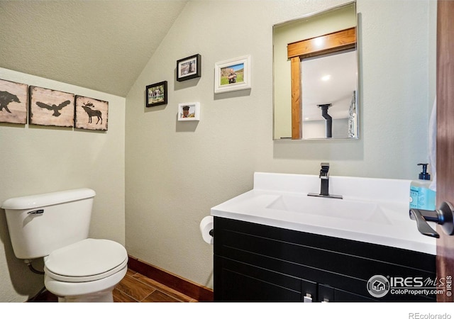 half bath featuring toilet, vanity, baseboards, wood tiled floor, and vaulted ceiling