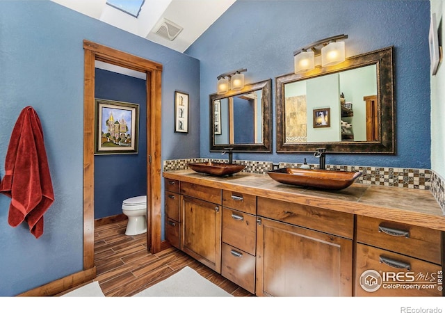 bathroom featuring a sink, visible vents, wood finish floors, and toilet