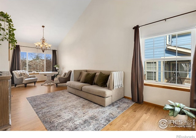 living room featuring a notable chandelier, wood finished floors, baseboards, and high vaulted ceiling