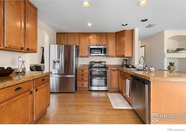 kitchen with a sink, stainless steel appliances, brown cabinets, and a peninsula