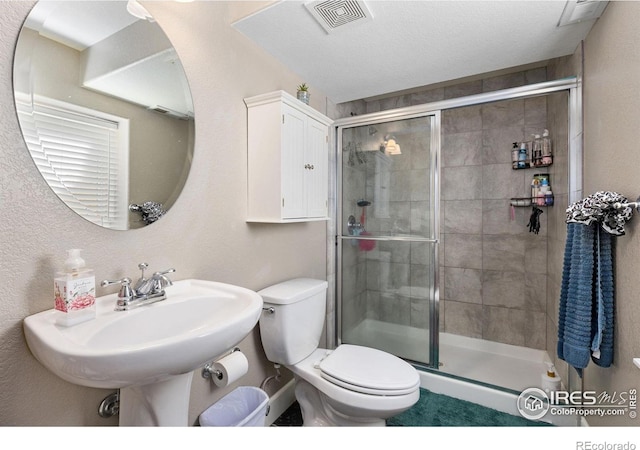 bathroom featuring visible vents, a shower stall, toilet, and a sink