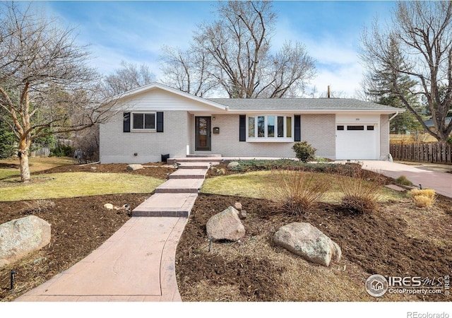 ranch-style house with a front yard, fence, driveway, a garage, and brick siding