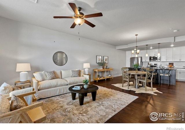 living room with dark wood-style floors, baseboards, and a ceiling fan