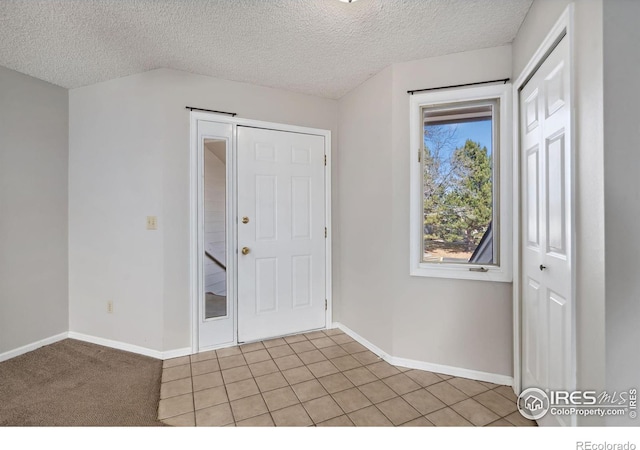 foyer featuring baseboards, a textured ceiling, and light tile patterned flooring