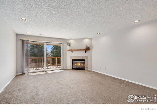 unfurnished living room with a tiled fireplace, recessed lighting, baseboards, and carpet floors