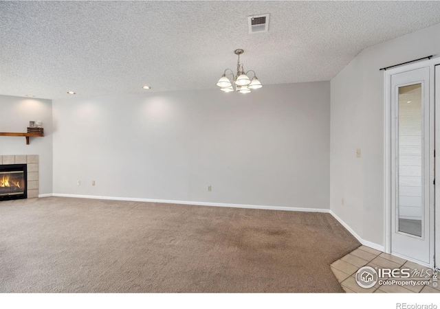 unfurnished living room featuring visible vents, carpet, a tiled fireplace, and a textured ceiling