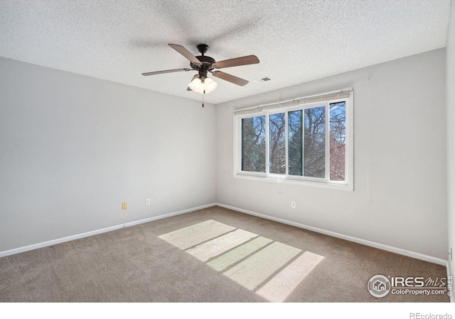 carpeted spare room featuring baseboards, visible vents, and a textured ceiling