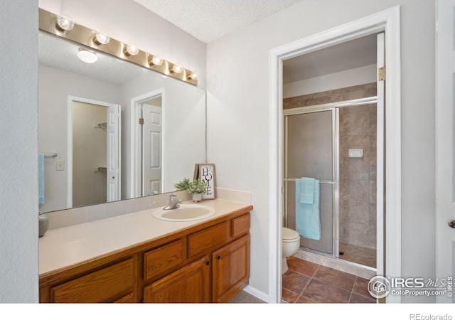 bathroom featuring vanity, tile patterned flooring, a shower stall, a textured ceiling, and toilet