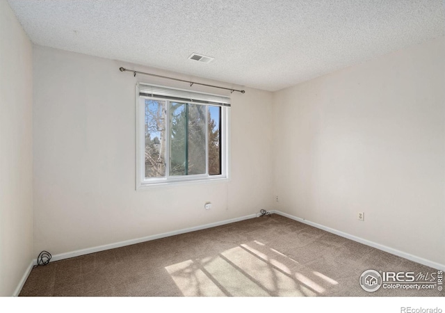 unfurnished room with visible vents, baseboards, carpet floors, and a textured ceiling