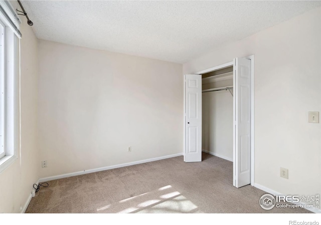 unfurnished bedroom with baseboards, carpet floors, a textured ceiling, and a closet