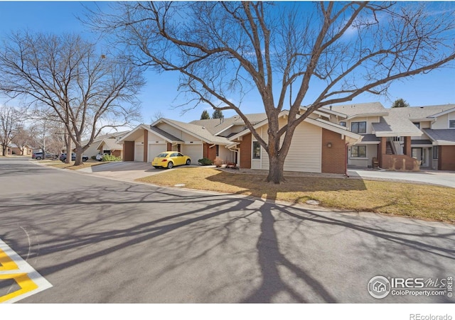 view of front of house with brick siding, a residential view, driveway, and a garage