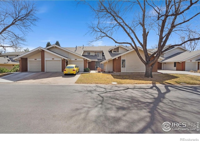 view of front of home featuring brick siding, a residential view, an attached garage, and driveway