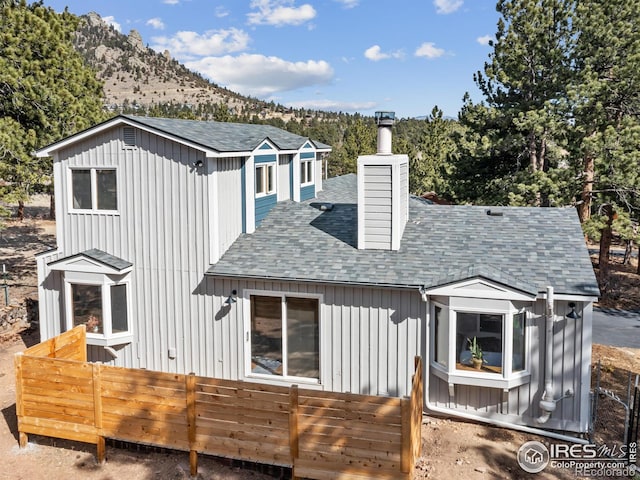 back of property with a chimney, a mountain view, board and batten siding, and a shingled roof