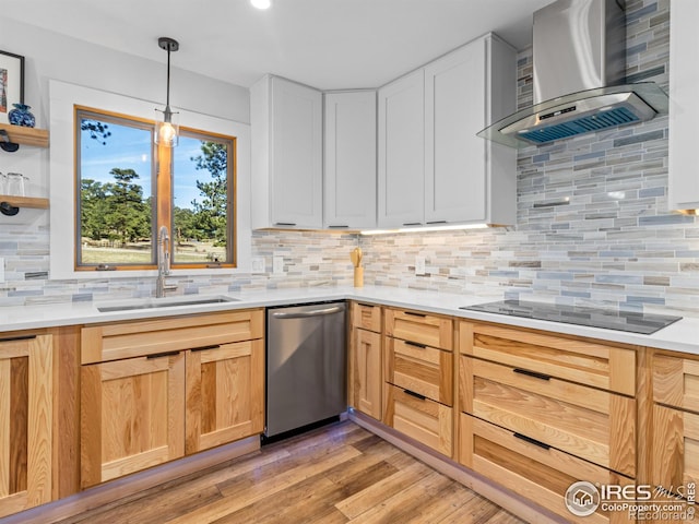 kitchen featuring a sink, wall chimney range hood, stainless steel dishwasher, light wood finished floors, and black electric cooktop