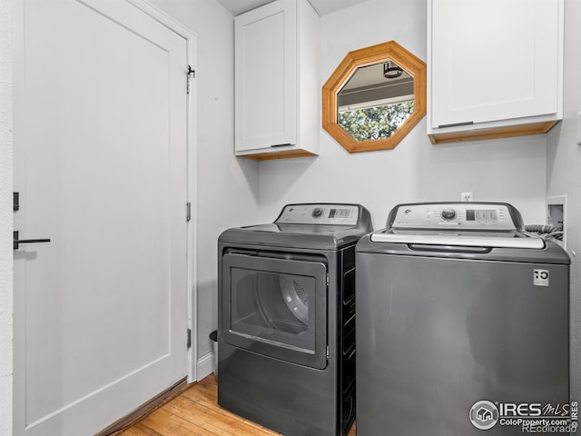 laundry area featuring light wood-style flooring, cabinet space, and washing machine and dryer