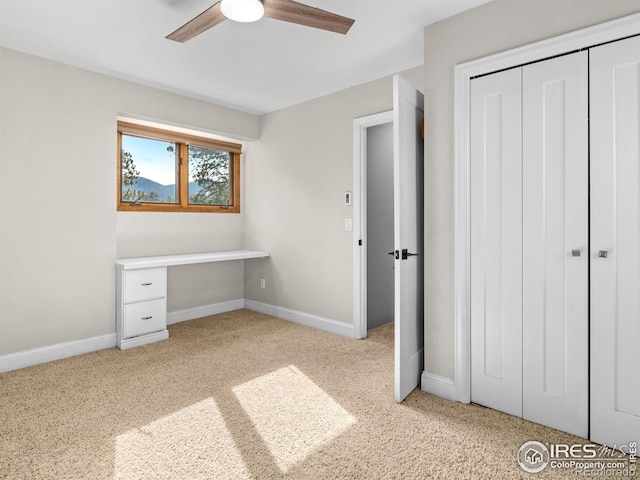 unfurnished bedroom with light colored carpet, baseboards, a closet, and ceiling fan