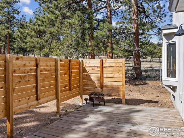 wooden terrace featuring a fire pit and a fenced backyard