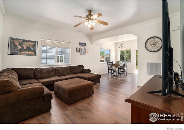 living room featuring crown molding, visible vents, dark wood-style flooring, and a healthy amount of sunlight