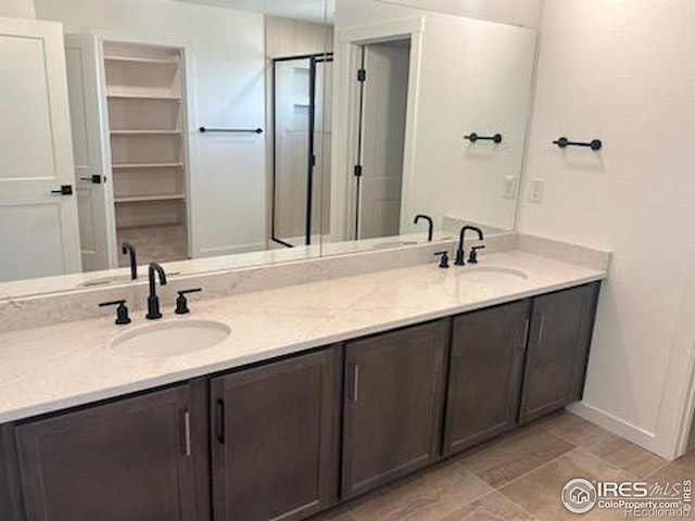 bathroom with double vanity, baseboards, and a sink