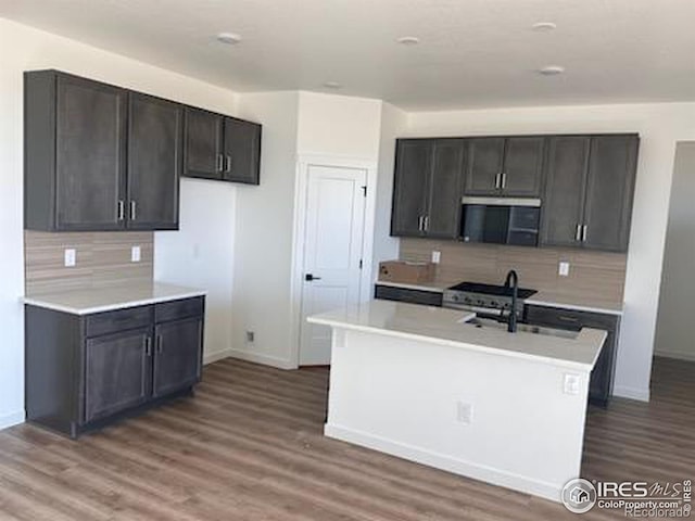 kitchen with tasteful backsplash, stainless steel appliances, light countertops, and wood finished floors