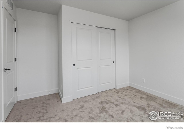 unfurnished bedroom with baseboards, a closet, and carpet floors